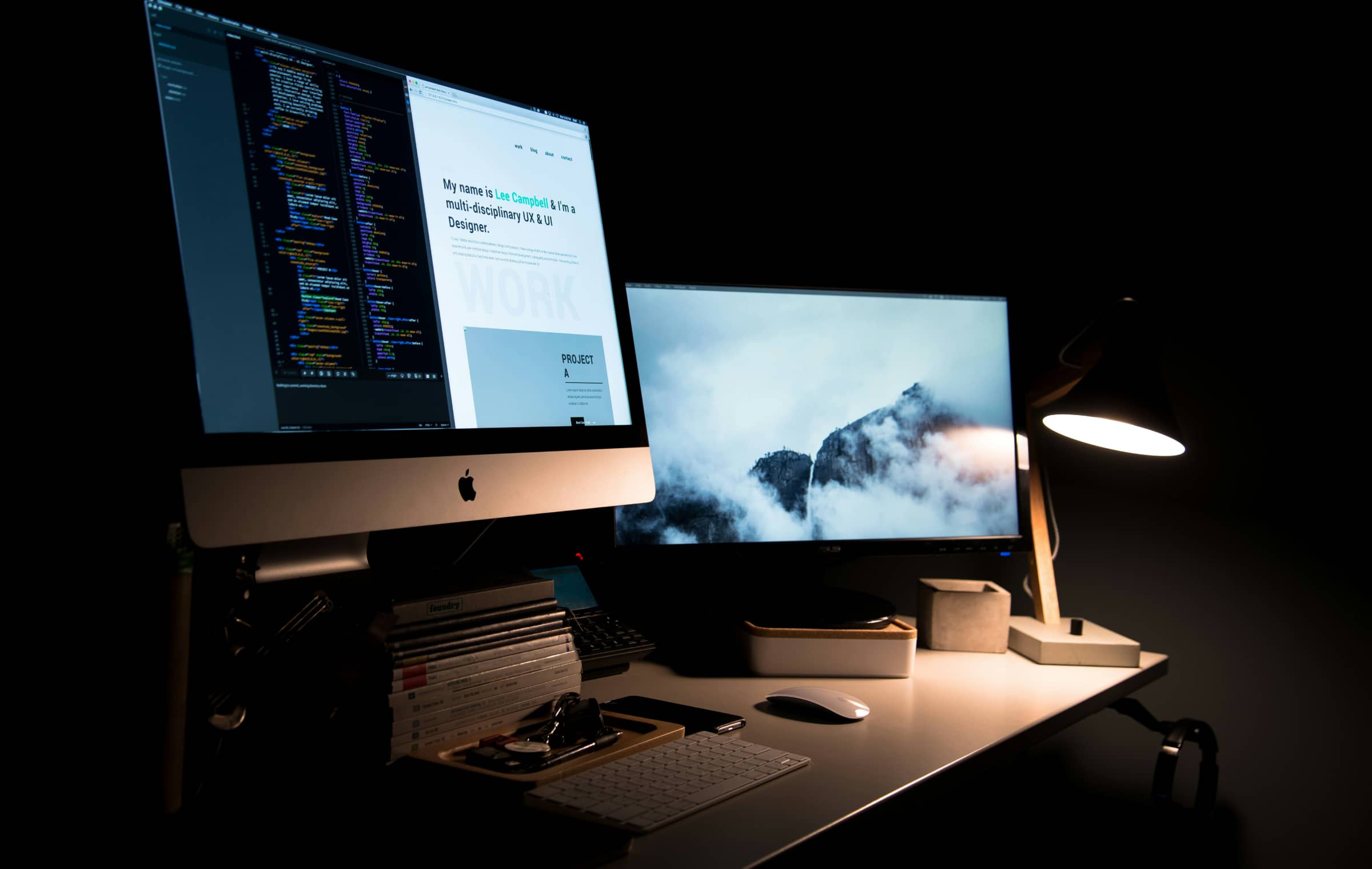 Two desktop screens and a lamp in a dark room