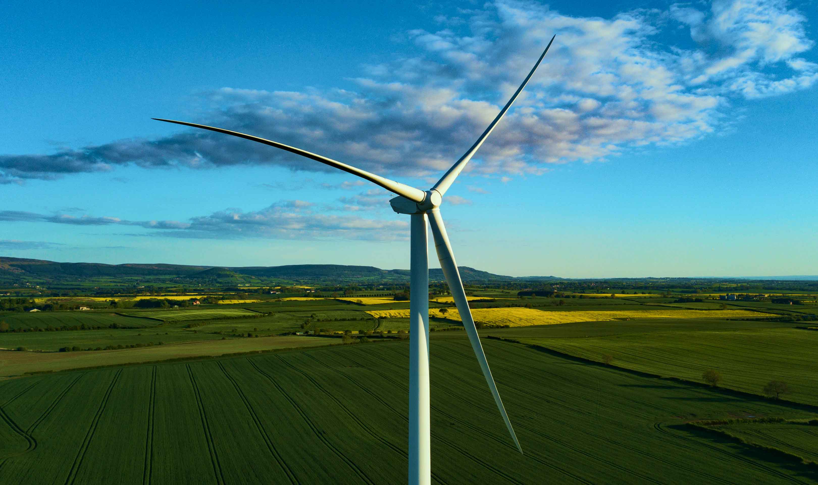 A white wind turbine on a field