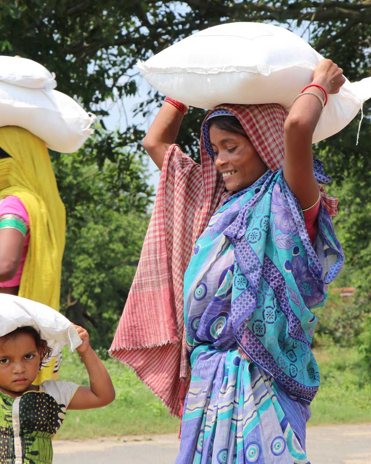 Two women and a kid carrying loads on their heads