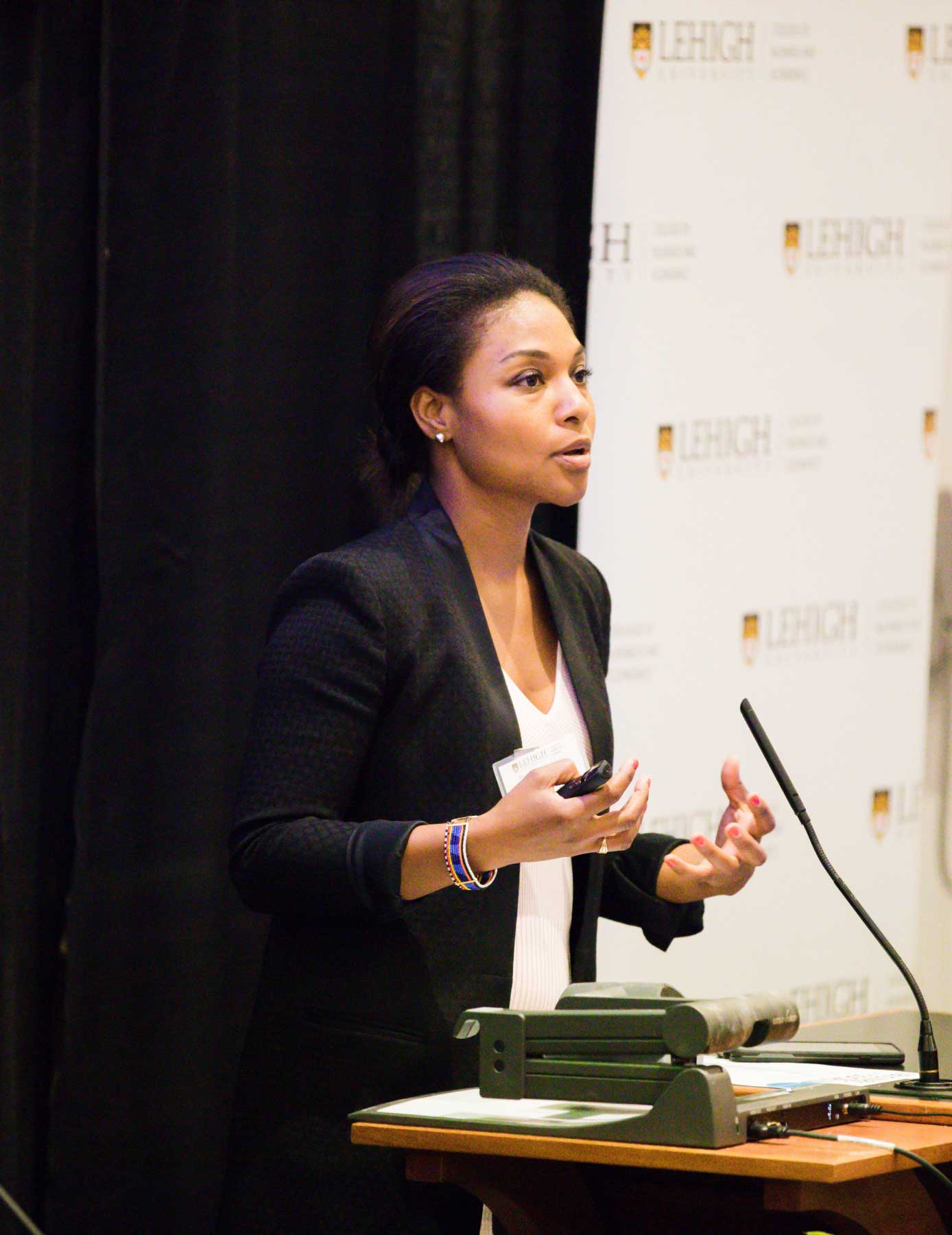 A woman is standing in front of the Lehigh podium, giving a speech.