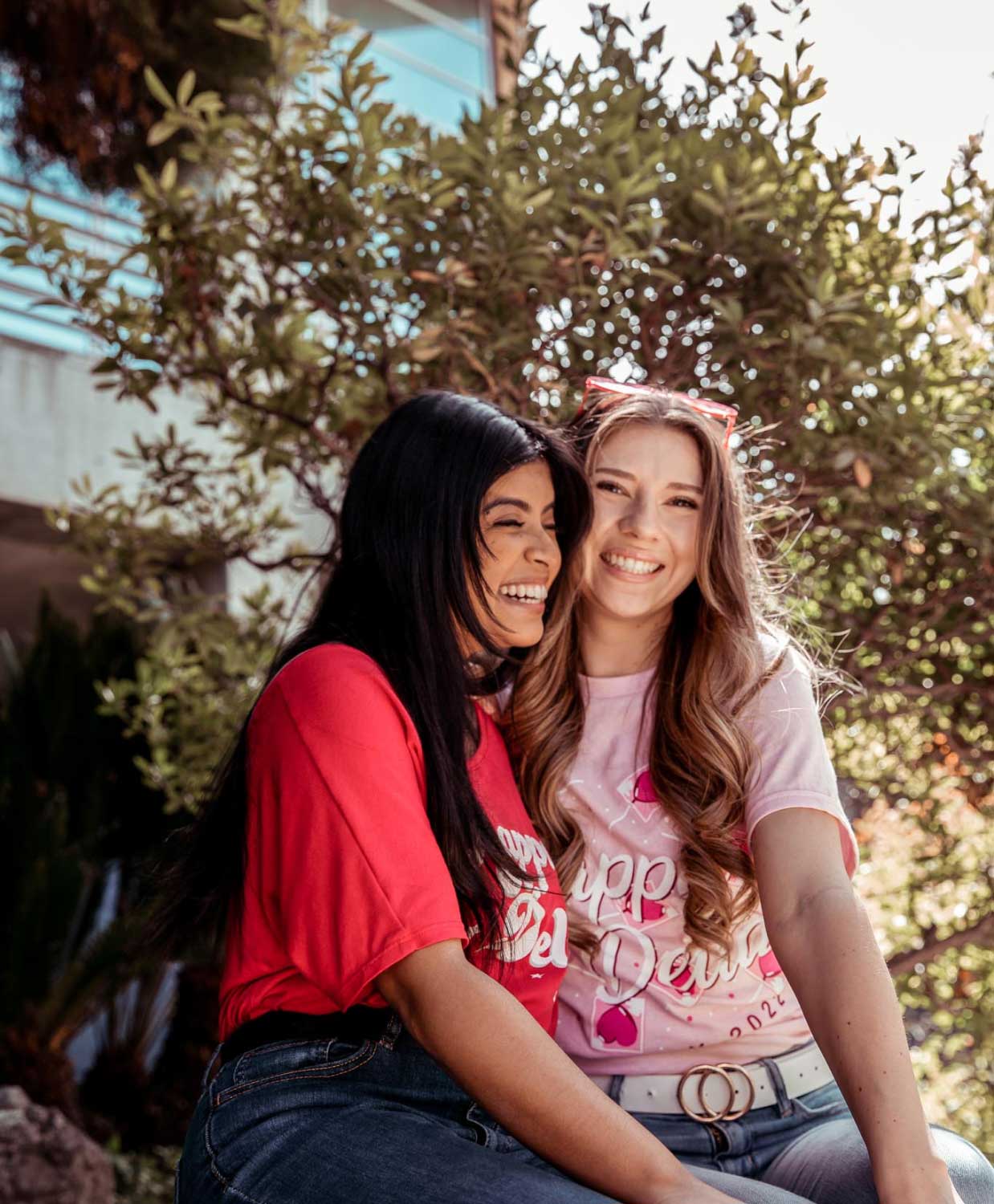 Two women sitting next to each other, smiling