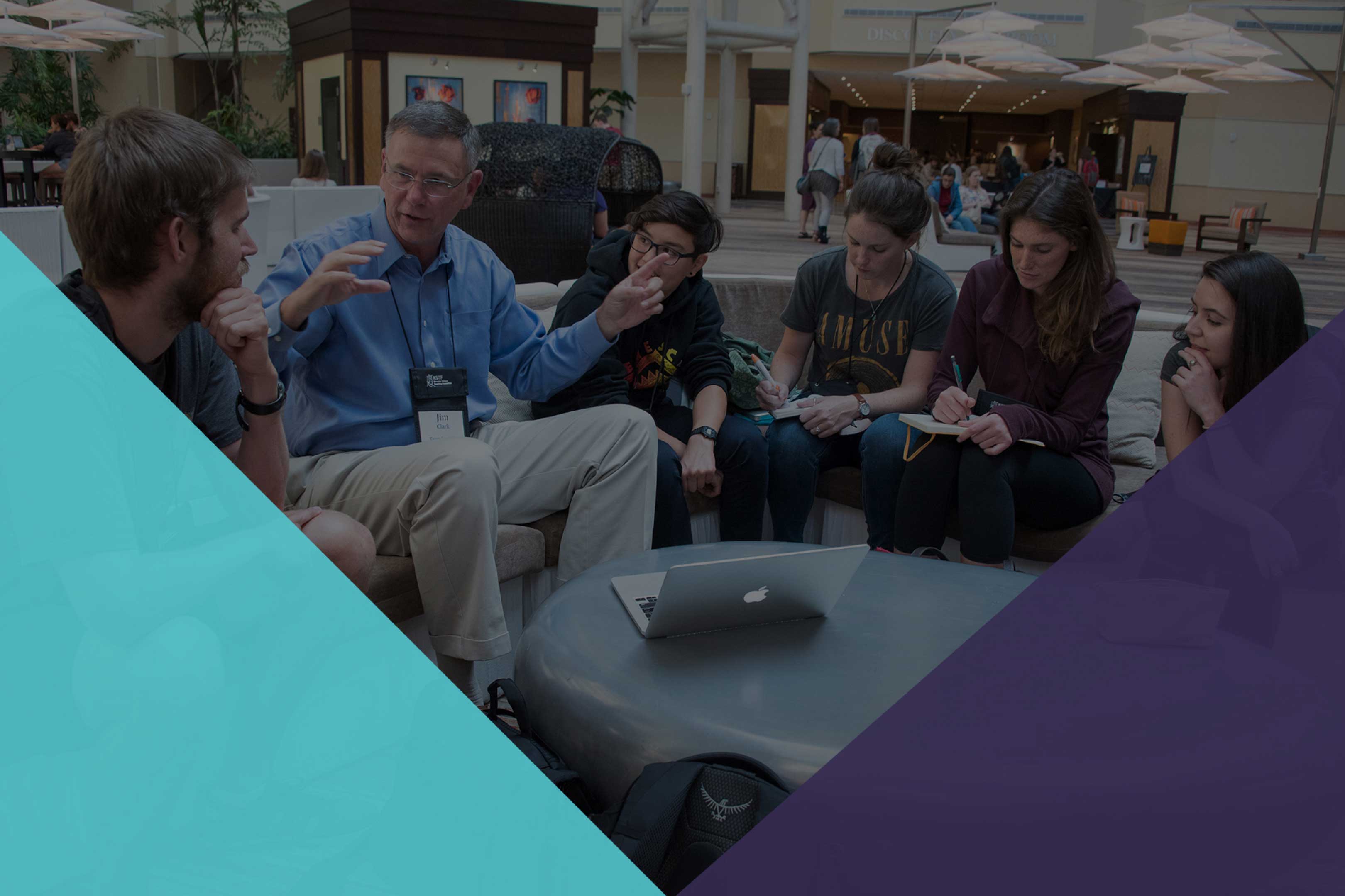 Knowles Teacher Initiative foundation branded image - a teacher and students are sitting around a round table while a teacher is talking to the students