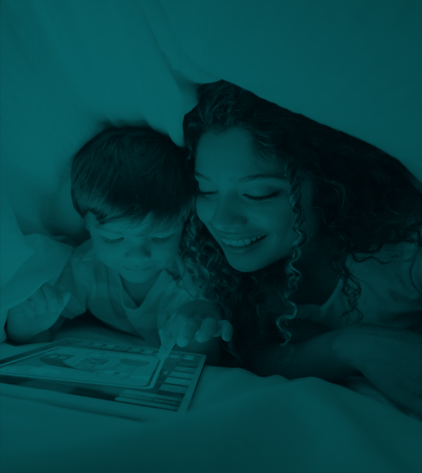 Woman and child reading a story on an ipad under the covers